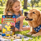 Child giving a golden retriever an Animal Crunchers biscuit beside the 12 oz box outdoors.